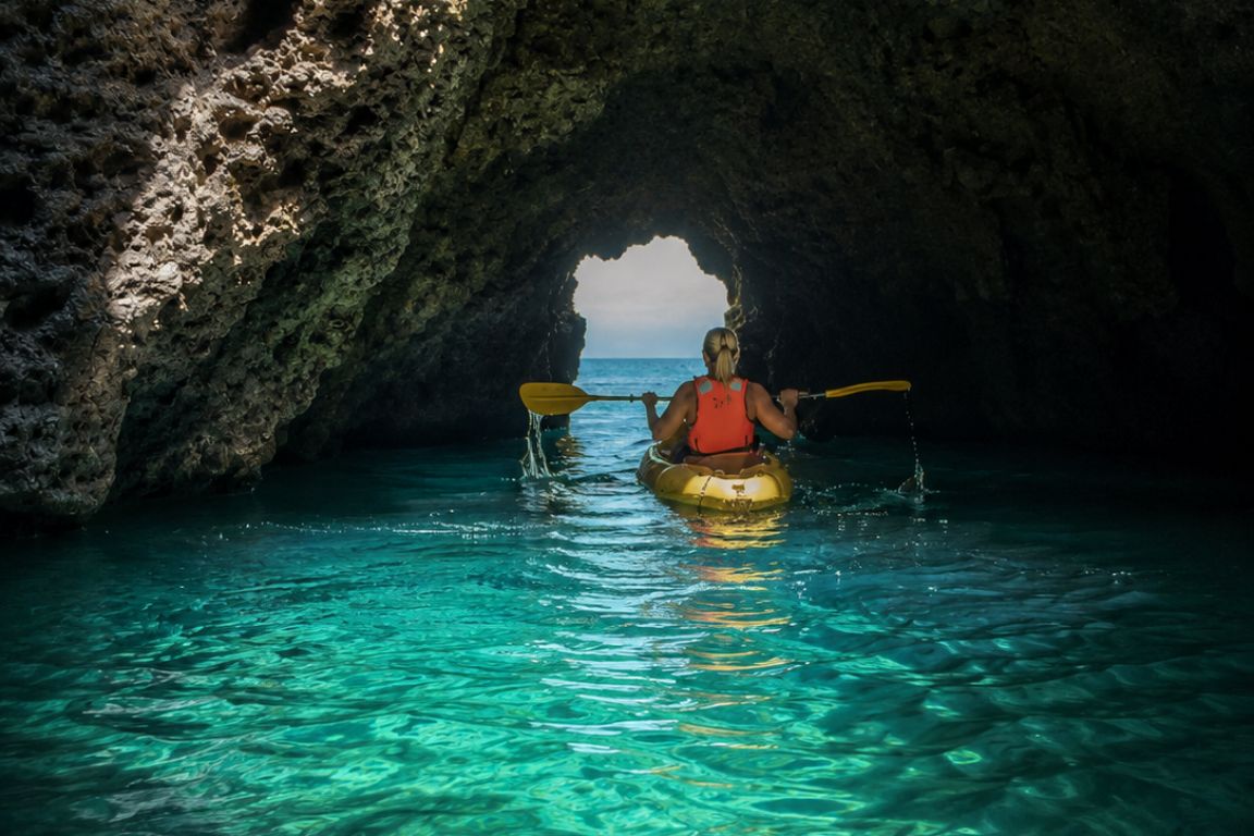 Traveler kayaking inside a beautiful sea cave near Lagos, Portugal during an unforgettable guided tour with Lagos Boat Tours